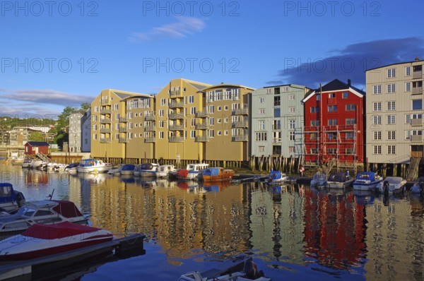 Wooden houses on the waterfront in the evening light with reflections and boats, harbour scene