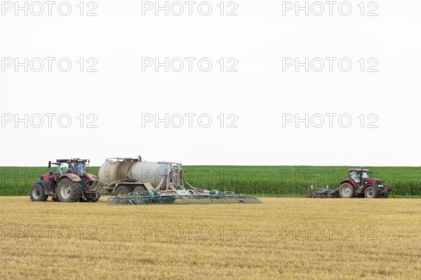 Farmers spread liquid manure on harvested grain field and plough it up, Swabian Alb,