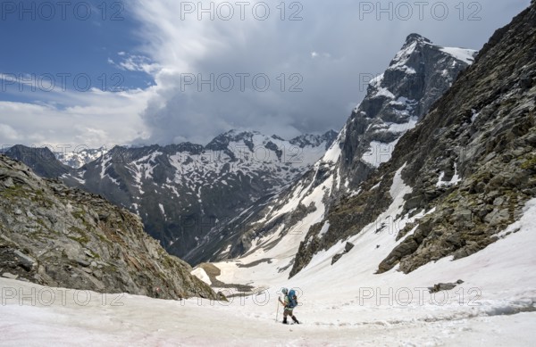Female mountaineer hiking in a snowfield, Nördliche Mörchnerscharte, behind mountain peak Greizer