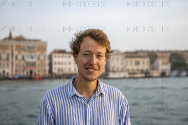 Young man in striped shirt, portrait, on the banks of the Grand Canal, looking into the camera,