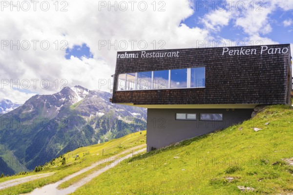 A modern restaurant on a mountain with a view of the surrounding mountains and meadows under a