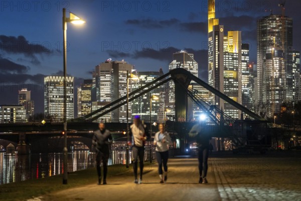 Skyline of the city centre of Frankfurt am Main, joggers on the pavement, promenade along the river