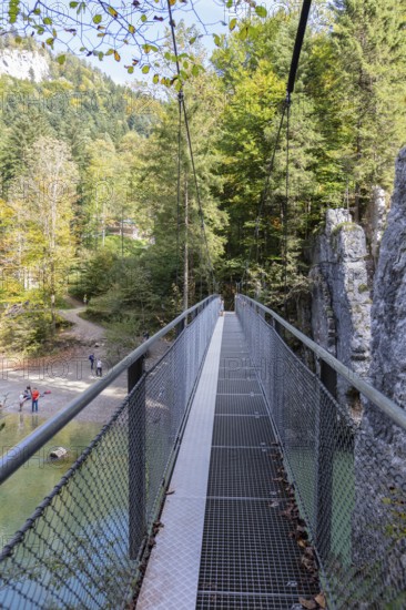 A long suspension bridge that leads through a rocky forest path, surrounded by nature, Klobenstein