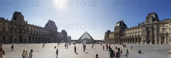 Panoramic view of the Louvre with the glass pyramid and numerous visitors under a clear sky, Paris