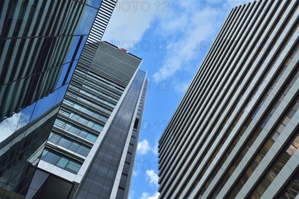 Tall modern skyscrapers with glass and steel facades against a bright blue sky with some clouds,