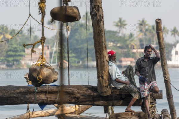 Fishermen resting, heavy stones attached to ropes, Chinese fishing nets, sunset, Arabian Sea coast,