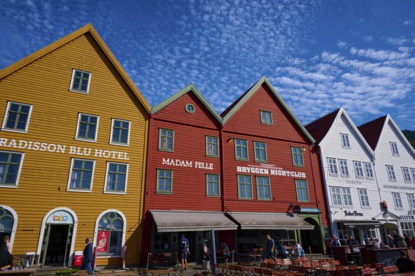Traditional wooden houses under a blue sky with pitched roofs and multiple windows in a sunny old