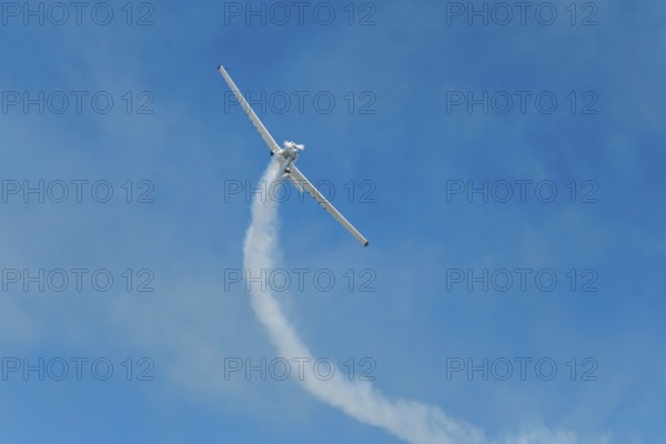 Stunt aerobatic plane performing stunts in blue sky with smoke trail. Concept of teamwork,
