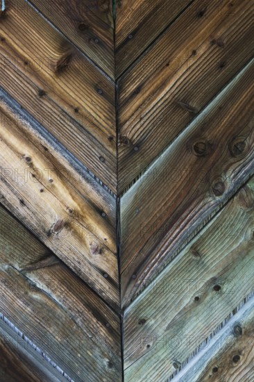 Close-up of of weathered pine wood planks assembled in V shaped patterns on exterior door, Quebec,