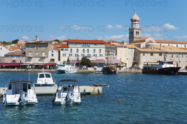 Various boats dock at the waterfront, with buildings and a bell tower in the background, Old Town,