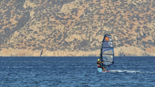 Windsurfer with view of rocky coast, clear blue water, windsurfer, Meltemi windsurfing area, Devils