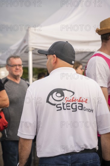 Security guard talking to festival visitors under a tent, Malleparty Böblingen, Germany, Europe
