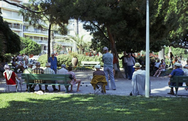 Men playing a game of boules in the shade of trees in a public park, Antibes, Côte d'Azur, France
