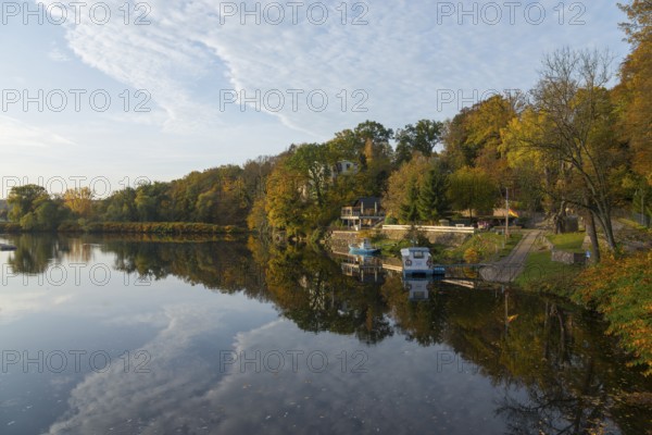 Idyllic river landscape in autumn with trees, boats and reflections in the water, River Mulde,