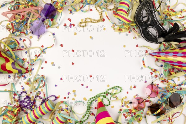 Colourful carnival paraphernalia such as hats, masks and confetti on a white background