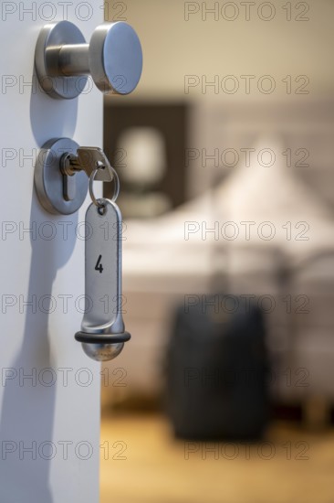 Symbolic image of a hotel, key inserted in the door of a hotel room, analogue lock