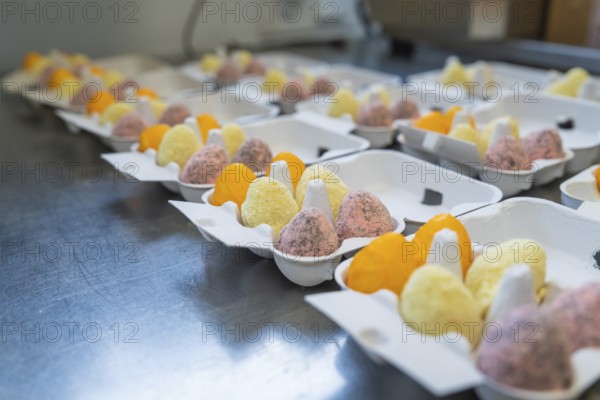 Colourful egg creations in packaging on a metal table, neatly lined up, Easter baking and chocolate