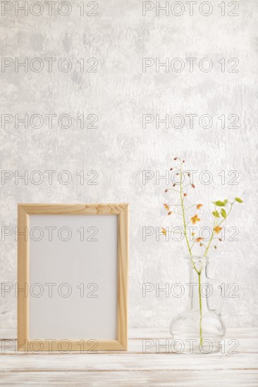 Wooden frame with orange barrenwort flowers in glass on gray concrete background. side view, copy