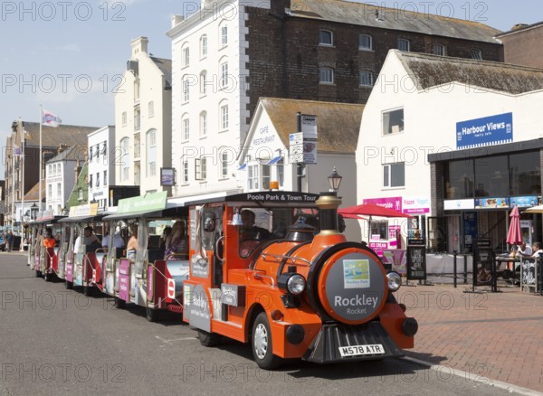 Rockley Rocket land train passing old historic buildings on quayside at Poole harbour, Poole,