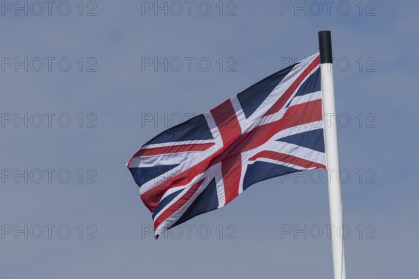 Union jack flag of the United Kingdom blowing in the wind against a blue sky, England, United