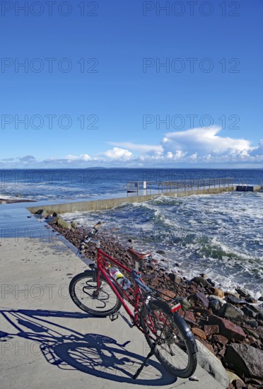 A red bicycle stands on a pier overlooking the sea on a sunny day, Tönsberg, Oslofjord, Norway,