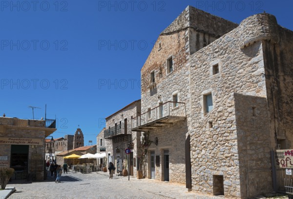 Sunny scene in an old town with historic stone buildings and people walking, Areopoli, Areopolis,