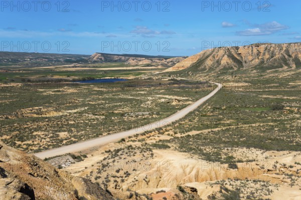 Wide landscape with a long road and hills under a clear blue sky, Bardenas Reales Natural Park,