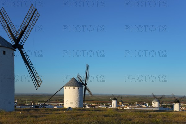 Windmills overlook a small village under a clear sky, Campo de Criptana, Ciudad Real province,