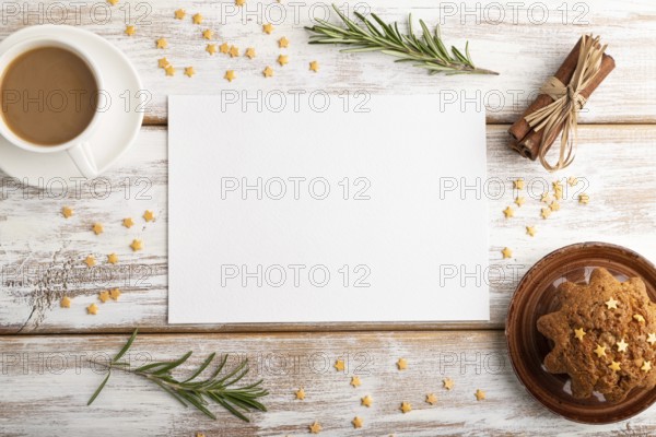 White paper sheet mockup with cup of coffee and cake on white wooden background. Blank, top view,