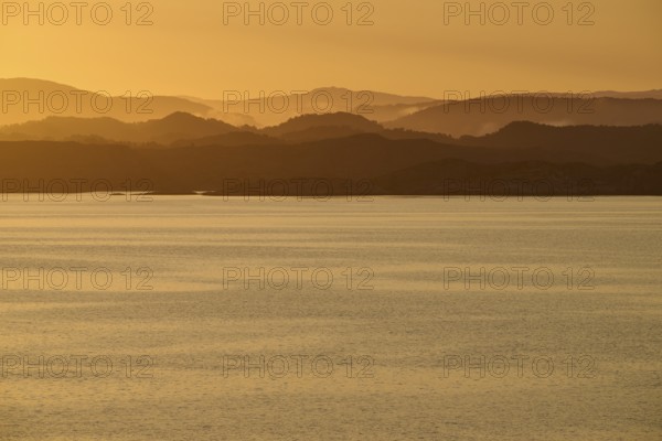 Calm atmosphere over the sea, hills and an orange sunrise, autumn, Bergen, North Sea, Norway,