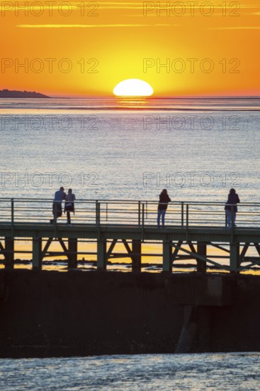Silhouettes of several people on the pier Freilaufkanal, couple and single persons watch from a
