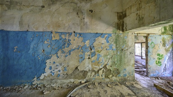 Blue and white peeling wall in a dilapidated room with partially visible graffiti, Lost Place,