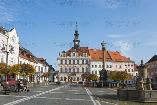 Historic town square with Baroque-style buildings and clock tower under a blue sky, town hall,