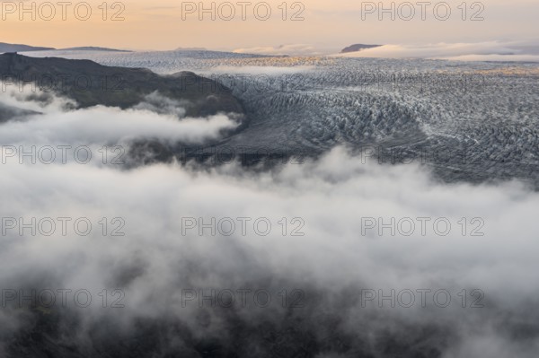 Fog, clouds moving around, glacier ice of the Kötlujökull glacier tongue at sunset, Myrdalsjökull