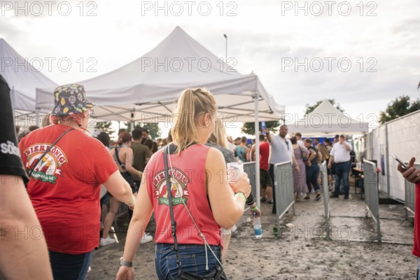 People in red T-shirts walk past white tents at a festival, Malleparty Böblingen, Germany, Europe