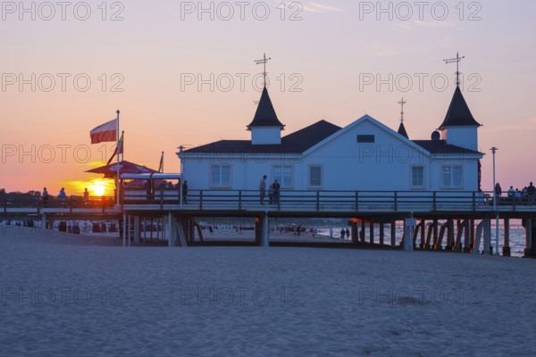 People strolling on a pier with buildings in the sunset, clear, blue, cloudless sky, pier Ahlbeck