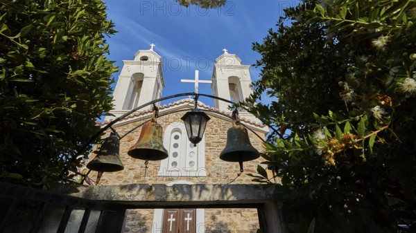 Three church bells in front of a stone wall under a deep blue sky, Koroni, Byzantine fortress,