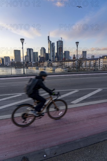 Skyline of the city centre of Frankfurt am Main, cyclist on the Ignatz-Bubis-Bridge, dusk, river