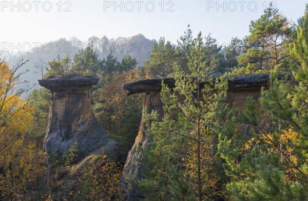 Three striking rocks in the evening light, surrounded by forest and hilly landscape in autumn, rock
