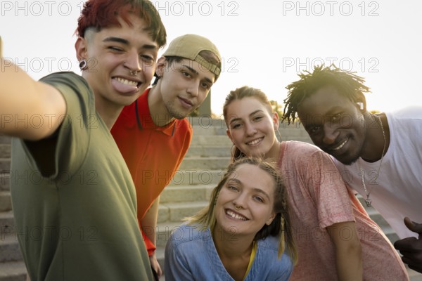 Happy friends of different cultures and races taking a selfie in the sunset light. Concept of youth