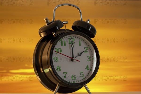 Symbolic image of the time change to summer time: close-up of an alarm clock in front of a