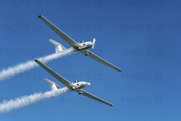 Stunt aerobatic plane performing stunts in blue sky with smoke trail. Concept of teamwork,