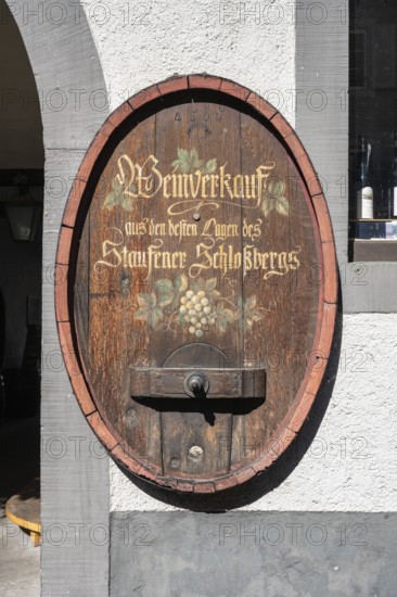 Old wine barrel on a house wall with artistic lettering and painting as a decorative advertising