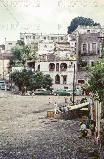 People and taxis at the Plaza bus stop, Hotel Colonia, Taxco, Guerrero state, Mexico, 1961, Central