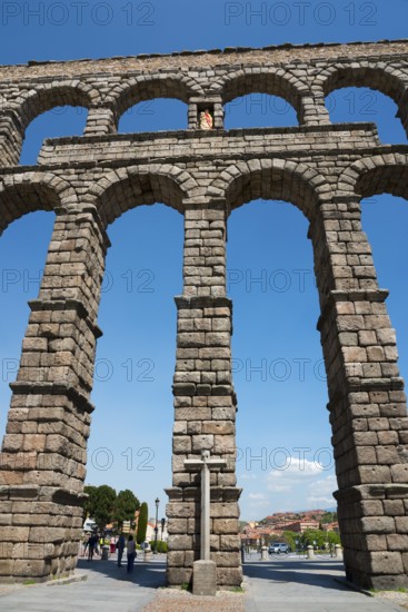 A majestic ancient aqueduct under a clear blue sky, with detailed stone arches, Aqueduct, Segovia,