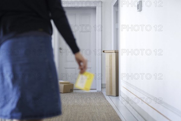 A woman walks through a stairwell in Berlin with a parcel collection note, 08/08/2024