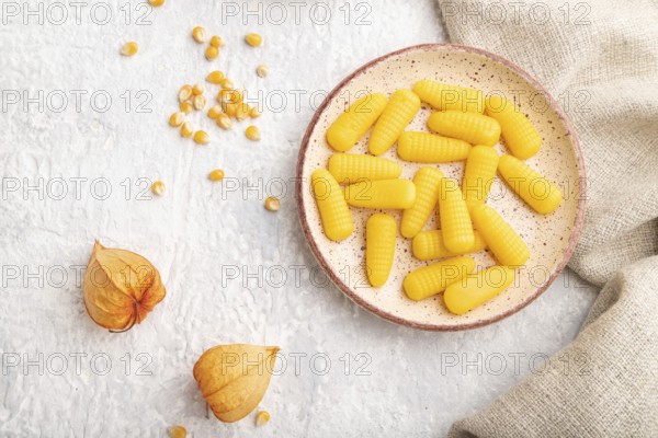 Jelly corn candies on gray concrete background and linen textile. top view, flat lay, close up