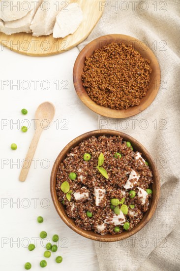 Quinoa porridge with green pea and chicken in wooden bowl on a white wooden background and linen