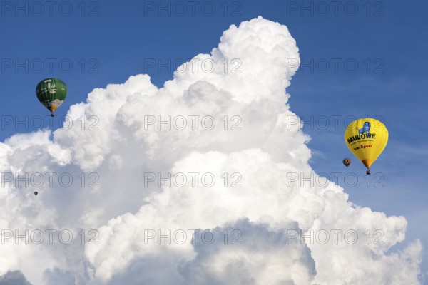 Two hot air balloons flying in front of big white clouds in the blue sky, Baden-Württemberg,