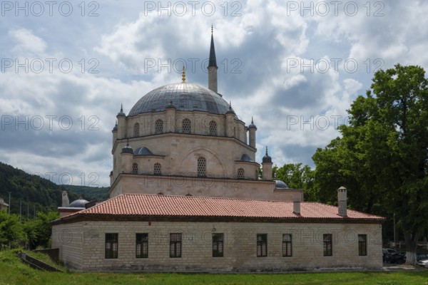 View of a mosque with dome and minaret, flanked by trees under a cloudy sky, Tombul Mosque, Sherif